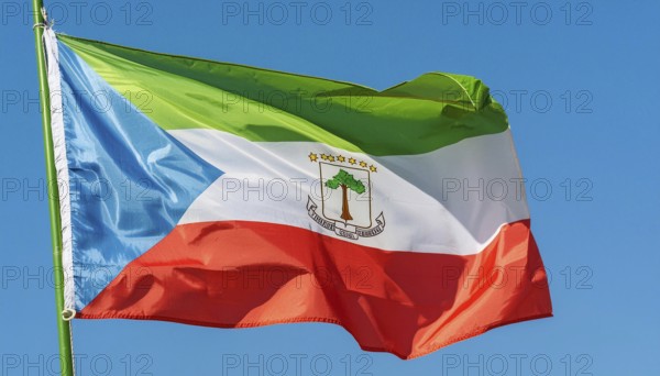 The flag of Equatorial Guinea flutters in the wind, isolated against a blue sky