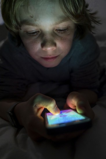 A boy plays computer games on a mobile phone, smartphone