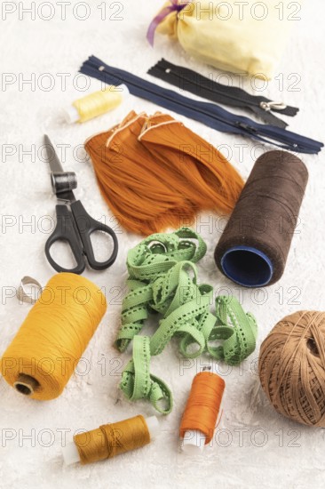 Sewing accessories: scissors, thread, thimbles, braid on gray concrete background. Side view, close