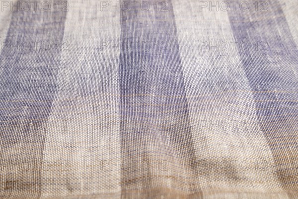 Fragment of smooth brown and violet linen tissue. Side view, natural textile background and texture