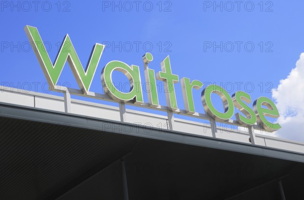 Green Waitrose supermarket shop sign against blue sky, Ipswich, Suffolk, England, UK