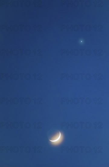 Narrow crescent moon with a halo (corona) and visible moon disc shortly after the new moon, evening