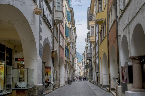 View through a lively pedestrian zone with arcades and shops, historic arcade in the old town