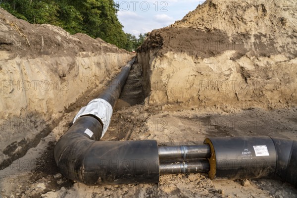 Laying of district heating pipes, next to a field, with maize, the district heating comes from a