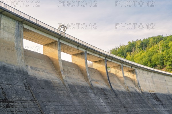 A large concrete dam rising against the sky, surrounded by green nature, Rappbodetalsperre, Harz