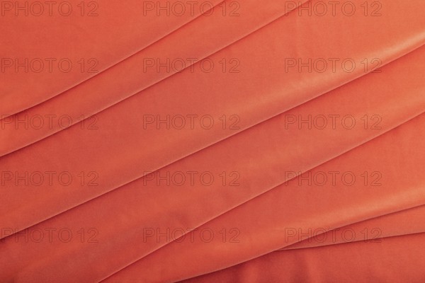 Fragment of red silk tissue. Top view, natural textile background and texture. wave concept,