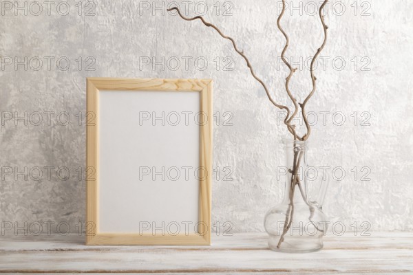 White wooden frame mockup with dried wine branch in glass on gray concrete background. Blank,