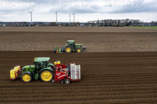 Early potatoes are laid in the soil of the field with a planting machine, tractor with roundabout