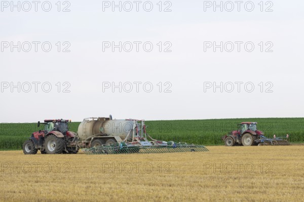 Farmers spread liquid manure on harvested grain field and plough it up, Swabian Alb,