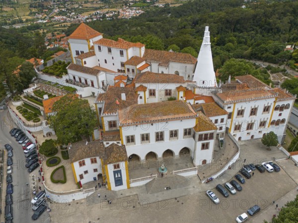 Aerial view of a historic castle with striking white towers and surrounding gardens, Royal Palace,