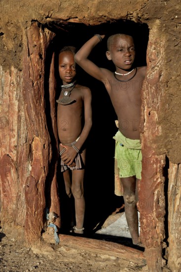 Himba children standing at the door of their hut, Omohanja, Kaokoland, Kunene, Namibia, Africa