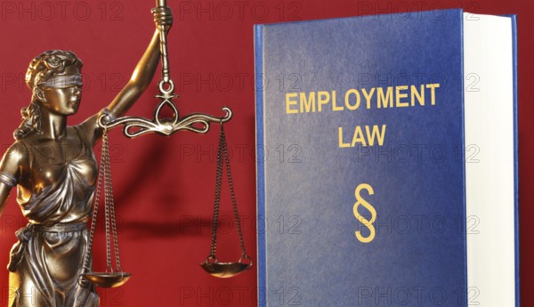Symbolic image: Reference book Employment law (labour law) and a Justitia