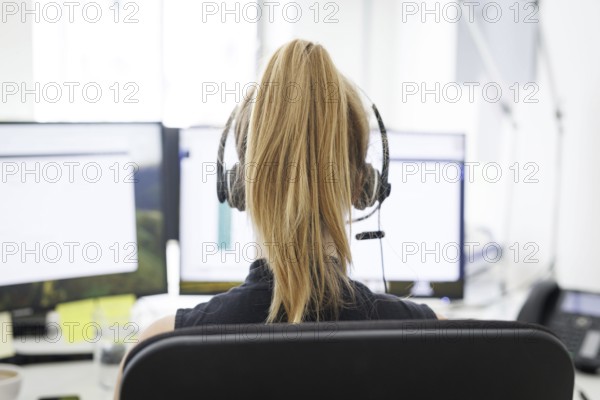 A woman wears headphones in an office in Berlin, 08.08.2024. Working in a call centre