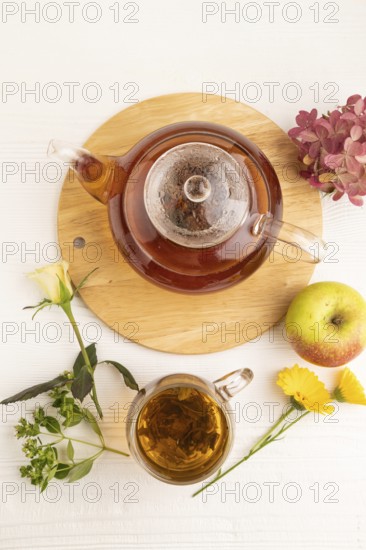 Red tea with herbs in glass teapot on white wooden background. Healthy drink concept. Top view,
