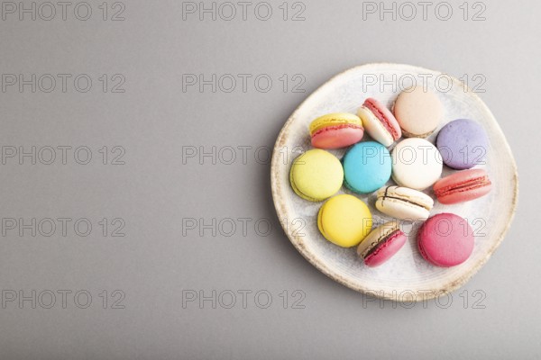 Multicolored macaroons on ceramic plate on gray pastel background. top view, copy space, still