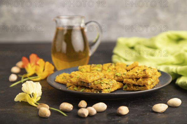 Traditional iranian dessert sohan with glass of green tea on a black concrete background and green