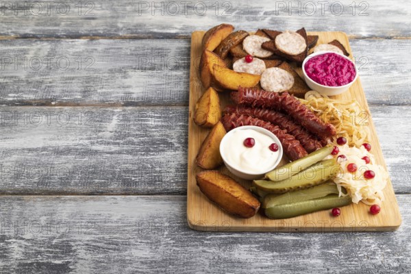 Set of snacks: sausages, toast, sauerkraut, marinated onion and cucumber, baked potato on a cutting