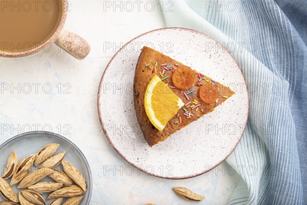 Orange cake with almonds and a cup of coffee on a white concrete background and blue linen textile.