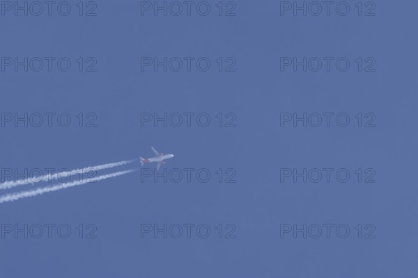 Airbus A320 aircraft of Easyjet airlines in flight with a contrail or vapour trail across a blue
