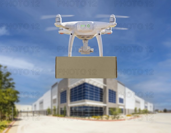 Unmanned aircraft system (UAS) quadcopter drone carrying blank package near corporate commercial