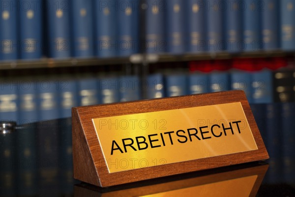 Symbolic image of labour law: Brass sign with the inscription Labour law in front of a large