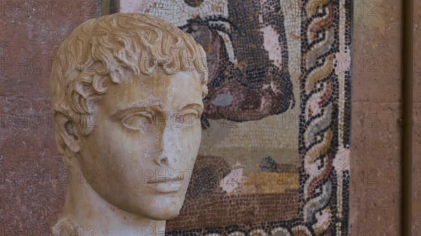 Classical portrait of an ancient marble bust, head of a young man, against a mosaic background,