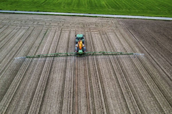 Farmer working a field, crop protection agent being sprayed, field with young sugar beet plants,