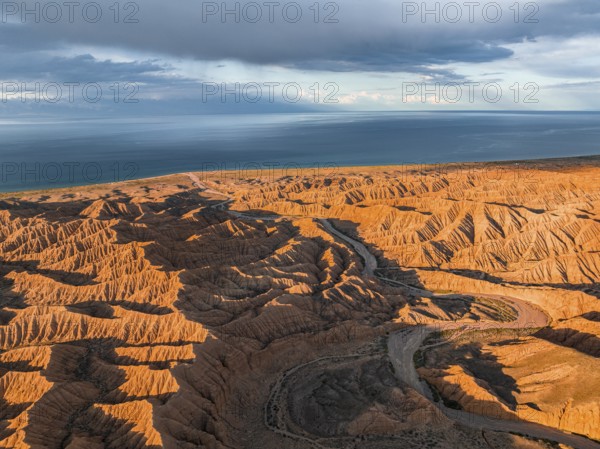 Riverbed runs through a landscape of eroded hills, badlands at sunset, Issyk Kul Lake in the