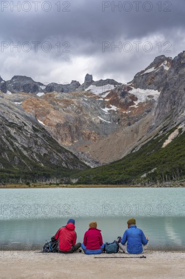Hikers sitting on the shore of the glacial lake Laguna Esmeralda, Tierra del Fuego Island,