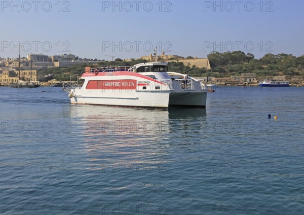 Mapfre Topcat ferry boat crossing harbour from Valletta to Sliema, Malta passing Fort Manoel