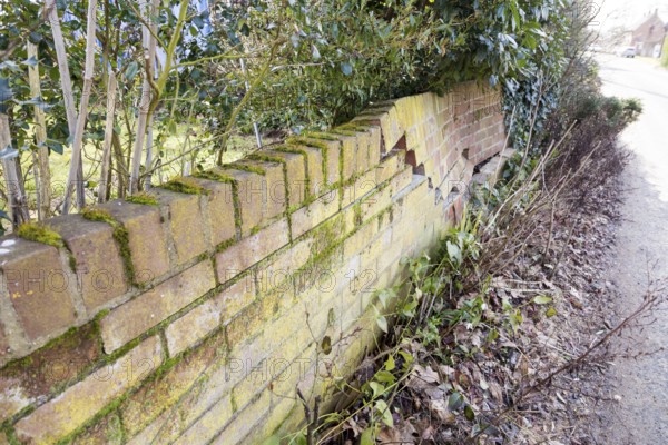 Impact damage to red brick garden wall caused by vehicle reversing, Suffolk, England, UK