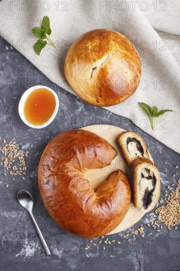 Homemade yeast buns and rolls with poppy seeds and honey on a black concrete background. top view,