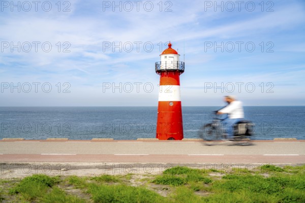 North Sea dyke near Westkapelle, Westkapelle Laag lighthouse, cyclists on the Zeeuwse Wind Route