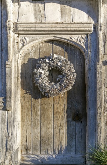 Silver white Christmas wreath on ancient old door in Lavenham, Suffolk, England, UK