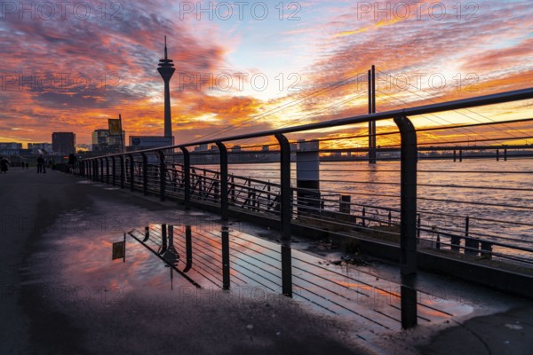 Winter sunset on the Rhine near Düsseldorf, riverside promenade at the old town, Rhine Tower, cargo