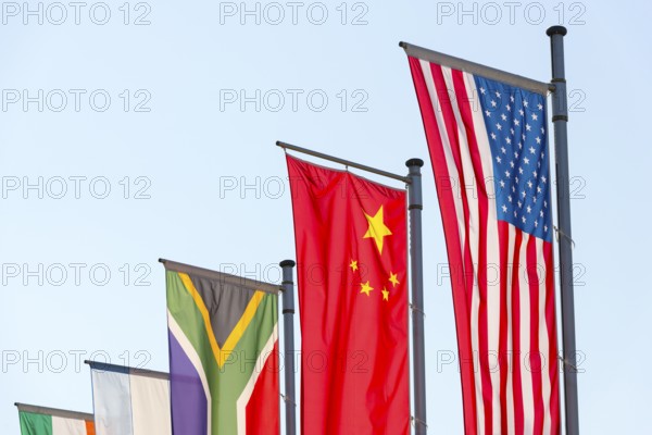 Various national flags fly on flagpoles against a blue sky, Chinese flag, American flag