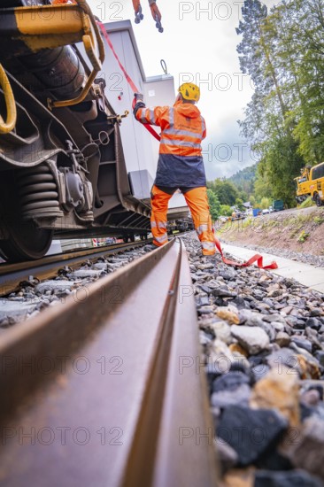 Railway worker in safety clothing works on a railway vehicle and fixes loose parts, surrounded by