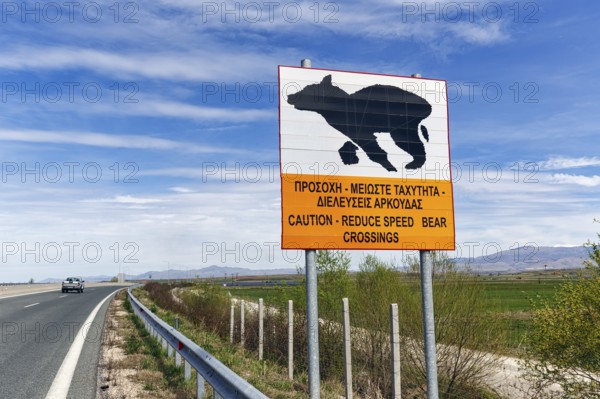 Bilingual warning sign on motorway, caution, drive slowly, bears crossing the road, Western
