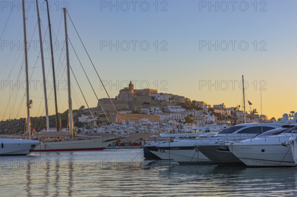 Luxury yachts anchored in the harbour, behind the fortress and the old town of Eivissa, Ibiza Town,