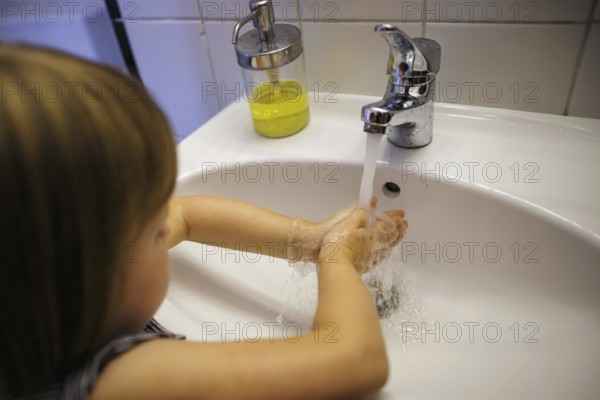 Symbolic photo: A small child washes its hands with soap and water at the bathroom sink. Berlin, 21