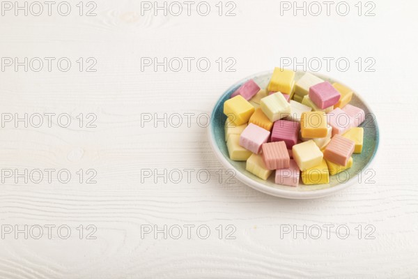 Various fruit jelly chewing candies on plate on white wooden background. apple, banana, tangerine,