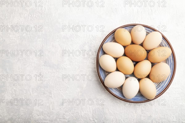 Pile of colored chicken eggs on plate on a gray concrete background. top view, flat lay, copy space