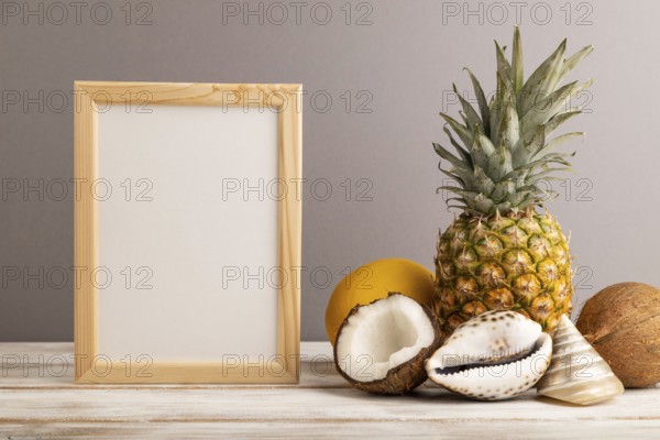 Wooden frame with melon, coconut, pineapple, seashells on gray pastel background. Side view, copy