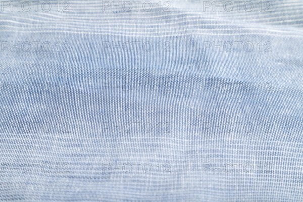 Fragment of smooth blue linen tissue. Side view, natural textile background and texture