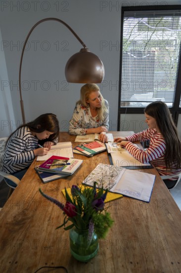 Homeschooling, during the lockdown in January 2021, mother helps her two daughters, at home,