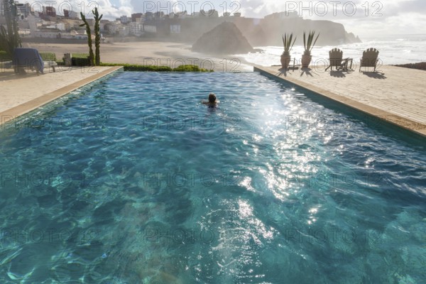 Woman swimming infinity pool by Atlantic Ocean, Hotel auberge Dar Najmat, Mirleft, Morocco, north