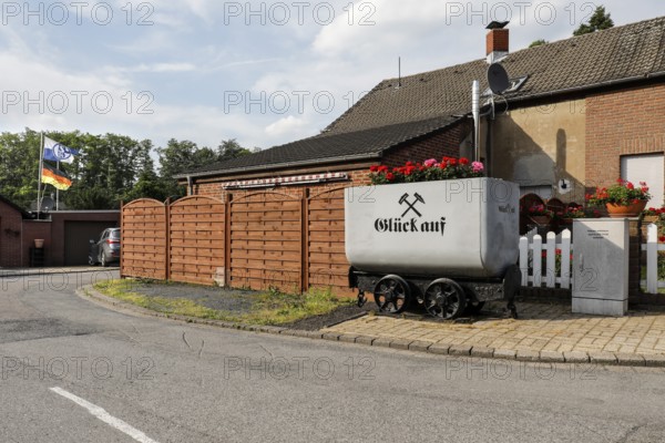A coal lorry with the miner's greeting Glück auf stands in front of a house in a housing estate in