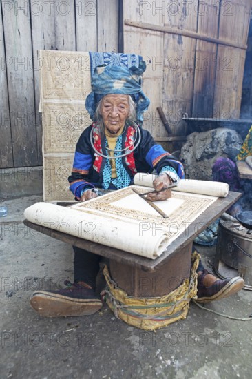 Vietnamese woman from the Hmong minority draws a pattern on linen fabric, Lung Tam linen weaving