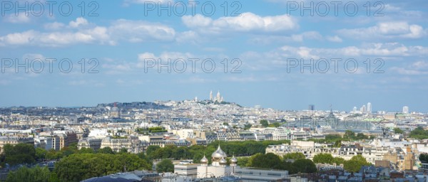 View over the rooftops of Paris on a sunny day in summer with few clouds, white city with some