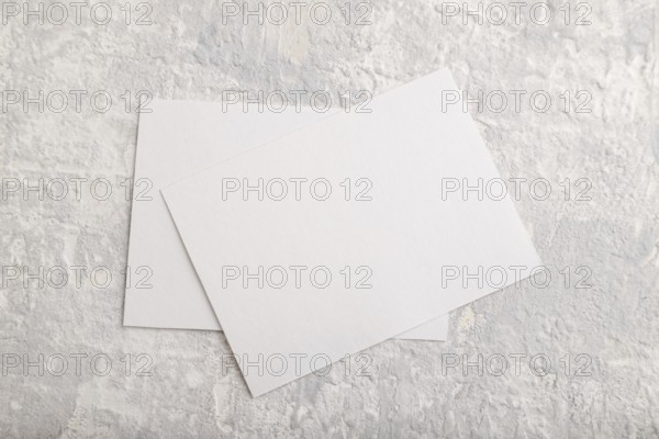 White paper business card, mockup on gray concrete background. Blank, flat lay, top view, still